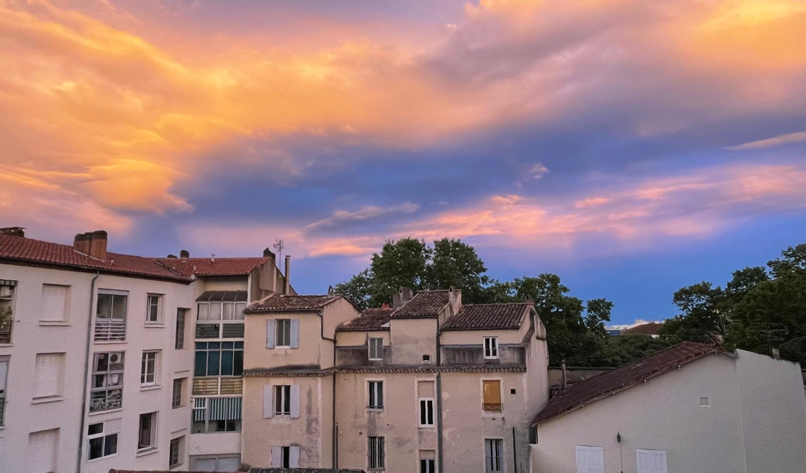 Photographie d'un lever de soleil derrière des immeubles du centre ville de Nîmes