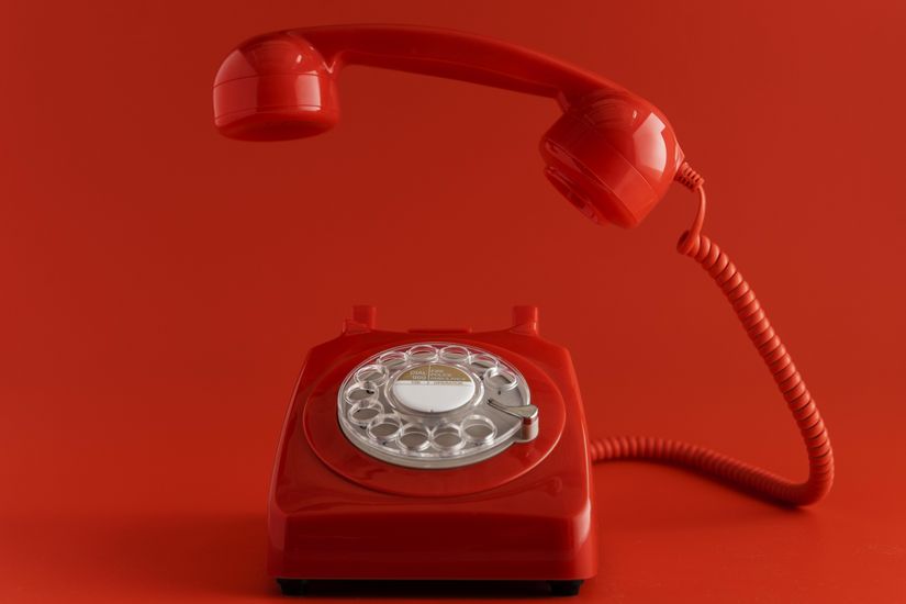 Photographie d'un téléphone vintage au combiné décroché, symbolisant un appel téléphonique