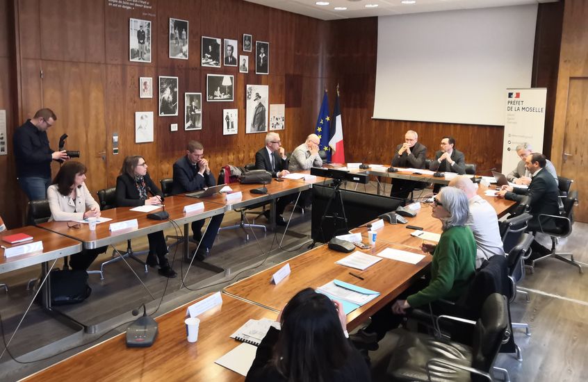 Photo de la réunion officielle autour d'une table en U dans les locaux de la prefecture de Moselle avec les différents acteurs impliqués dans la démarche.